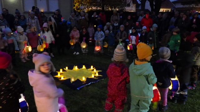 Kindergartenkinder mit beleuchteten Laternen bei einem Laternenfest